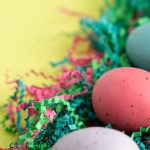 Vibrant Easter eggs lying on colorful shredded paper, perfect for spring celebrations.